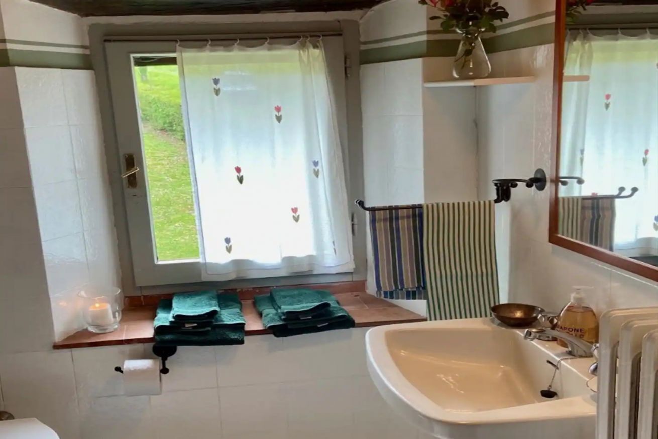 A bathroom with a window, a sink, a mirror, and a towel rack.