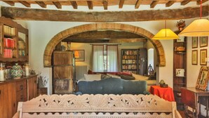 Un dormitorio con una cama grande, un arco de entrada, una estantería y una mesa roja.