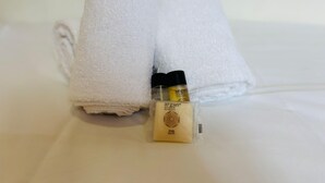 Zwei ordentlich gefaltete weiße Handtücher und eine kleine Seifenflasche auf einem Bett.