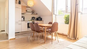 Una cocina moderna con comedor, suelo de madera y un amplio ventanal con cortinas.