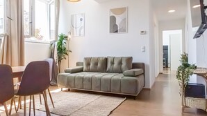 Una sala de estar moderna con un sofá, una mesa de comedor con sillas, una lámpara colgante y obras de arte en las paredes.