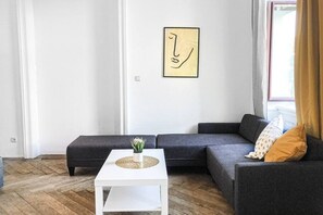 A modern living room with a gray sectional sofa, a white coffee table, and a minimalist wall art piece.