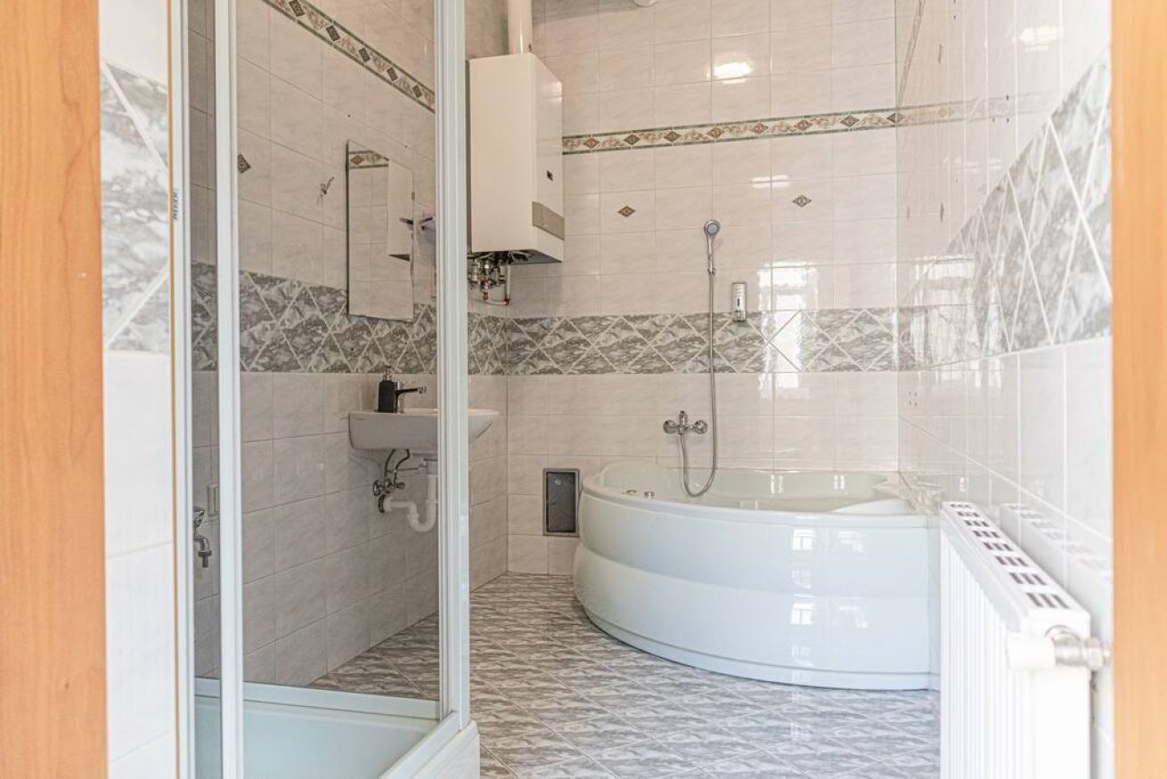 Ein Badezimmer mit Duschkabine aus Glas, einer weißen Badewanne und einem Waschbecken mit Spiegel darüber.