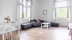 Un salon moderne avec un canapé, une table à manger et des chaises, ainsi que de grandes fenêtres.