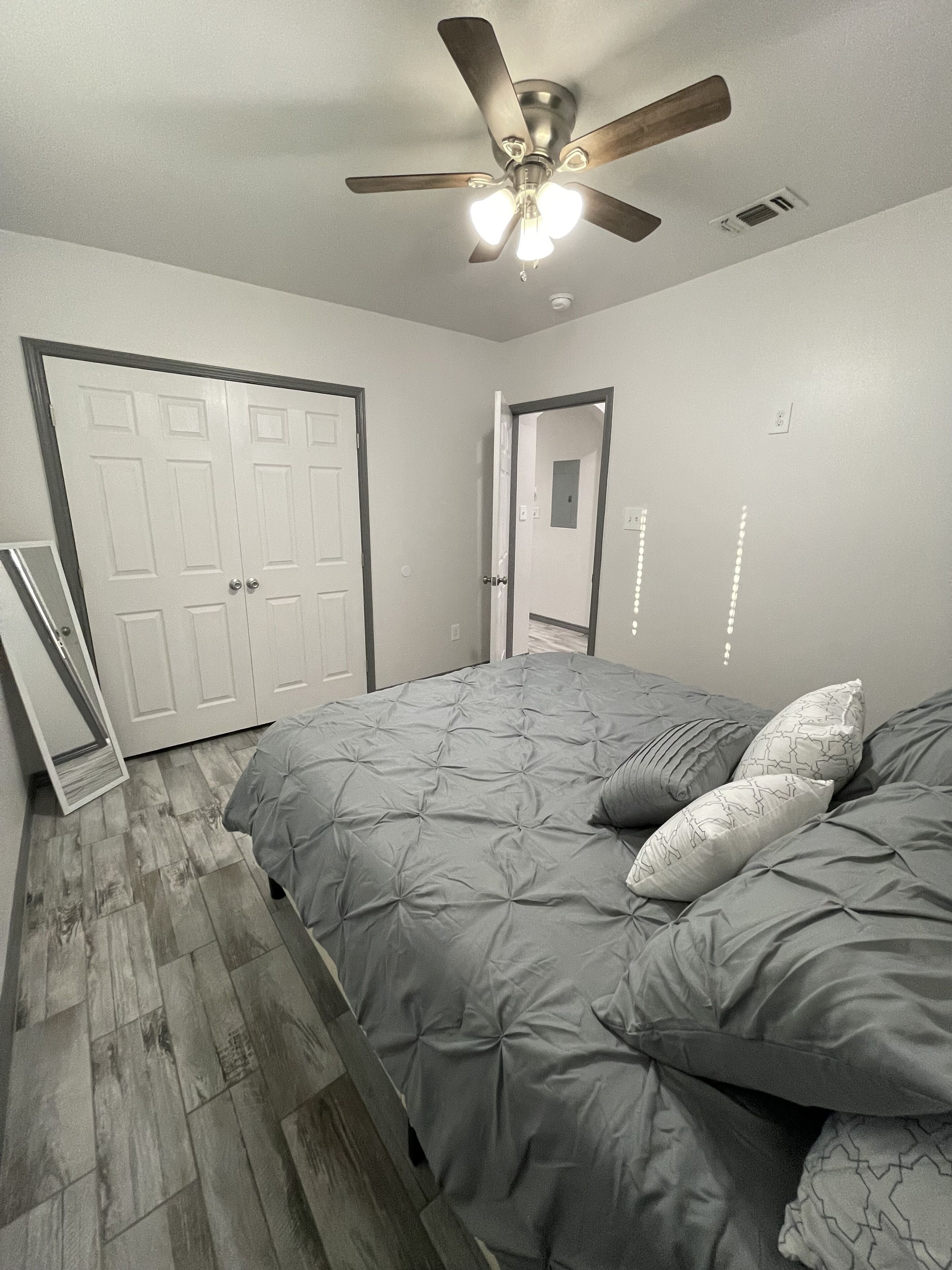Une chambre à coucher avec un lit, un ventilateur de plafond et une porte.