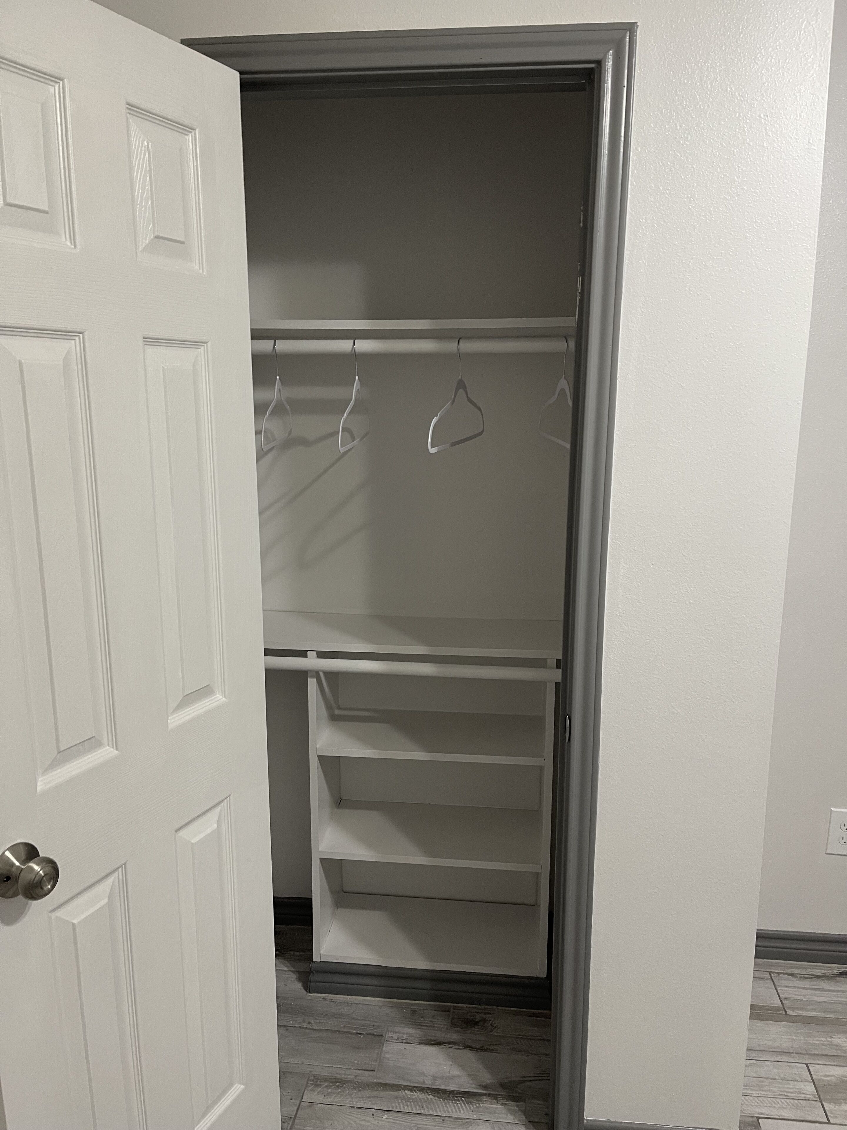 A walk-in closet with a door, shelves, and hanging space.