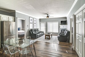 Un salon moderne avec une table à manger en verre, des canapés en cuir et un ventilateur de plafond.