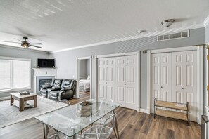A modern living room with a glass dining table, leather seating, and a fireplace. - Pet-Friendly Waukee Condo: 14 Mi to Des Moines! (Waukee)