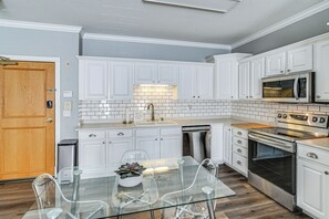 A modern kitchen with white cabinetry, a stainless steel oven, and a microwave.