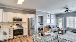 Una cocina moderna con armarios blancos, electrodomésticos de acero inoxidable y una mesa de comedor de vidrio.