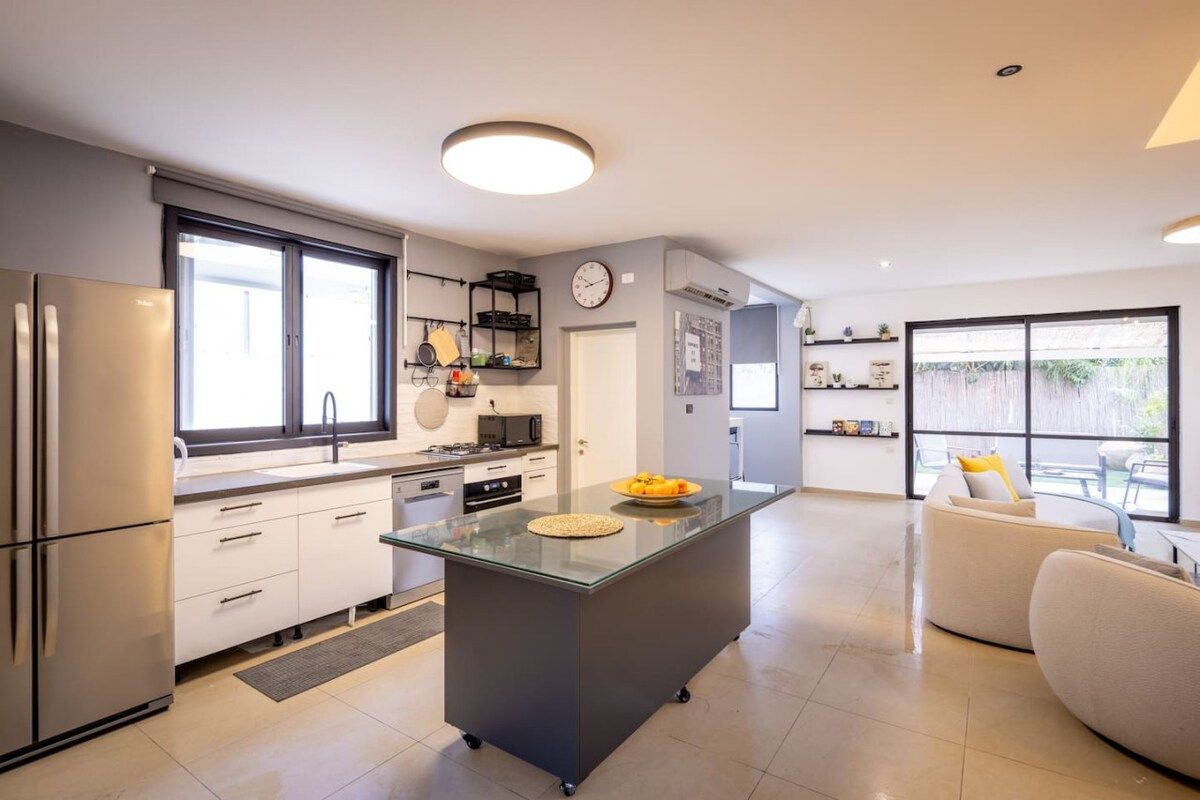 A modern kitchen with a central island, built-in appliances, and a dining area with a sofa.