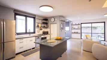 A modern kitchen with a central island, built-in appliances, and a dining area with a sofa.
