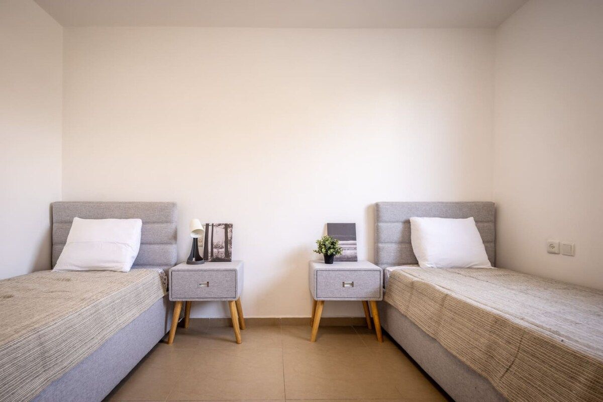A twin room with two single beds, bedside tables, and a small potted plant.