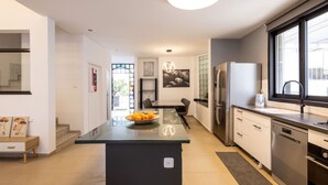 A modern kitchen with a central island, stainless steel appliances, and a large window providing natural light.