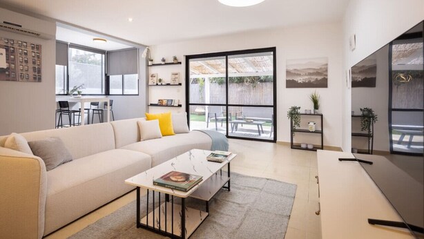 A modern living room with a sofa, coffee table, and a large window.