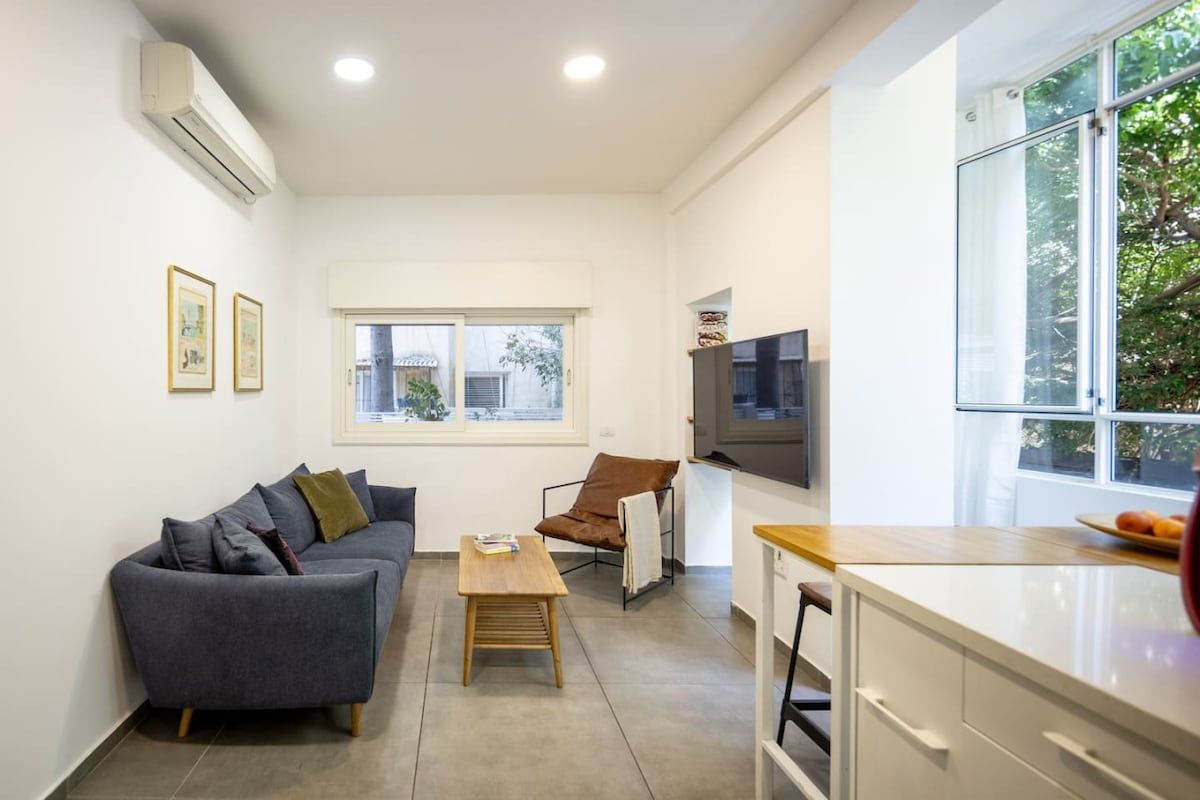 Un espace de vie moderne comprenant un canapé, une table basse, un téléviseur et une fenêtre.