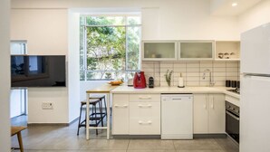 Una cocina moderna con armarios blancos, horno empotrado y ventana que deja entrar luz natural.