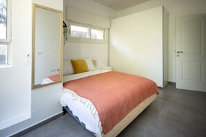 Une chambre à coucher avec un lit, une fenêtre, une porte et un miroir.