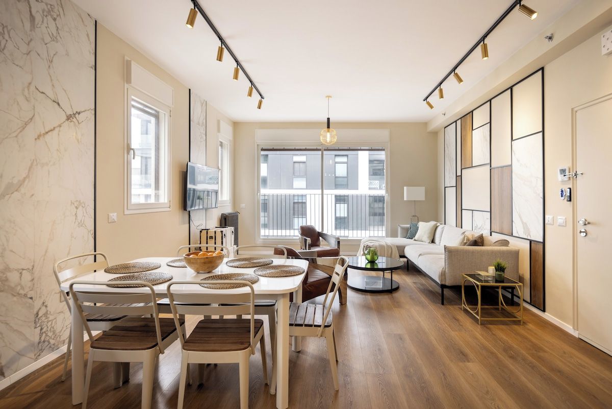 A modern living room with a dining area, large windows, and a sofa.