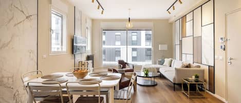 Una sala moderna con comedor, ventanas amplias y un sofá.