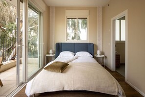 Un dormitorio con una cama grande, un ventanal y un balcón.