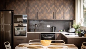Una cocina moderna con salpicadero de espiga, electrodomésticos de acero inoxidable y un comedor con individuales tejidos.