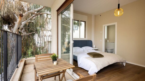 Un dormitorio con cama, mesita de noche y ventana.