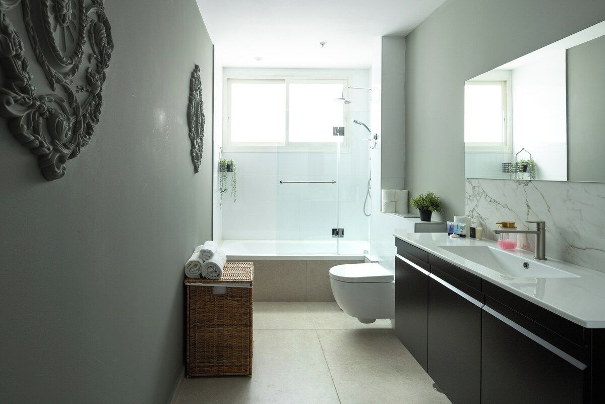 Un baño moderno con cabina de ducha de vidrio, inodoro blanco y encimera de mármol.