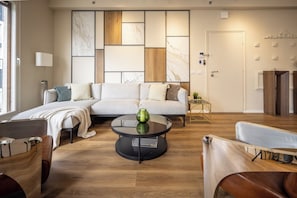 Ein modernes Wohnzimmer mit einem Ecksofa, einem runden Couchtisch und Holzboden.