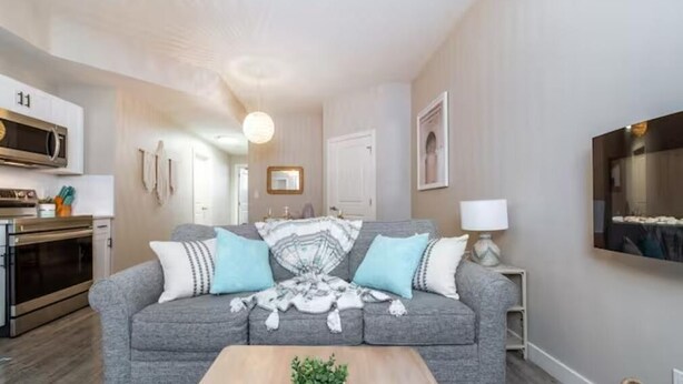 A modern living room with a grey sofa, a coffee table, and a TV on the wall.