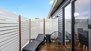 Un espace extérieur aménagé en terrasse, avec des sièges, une porte vitrée et une plateforme en bois.