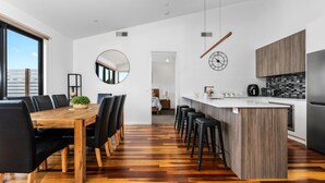 Une cuisine moderne avec une table à manger en bois, des chaises noires et un îlot central doté de tabourets.