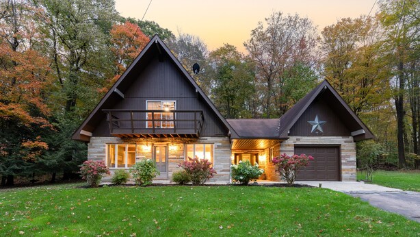 A two-story log cabin with a stone foundation, a large front porch, and a garage. - Laurel Highlands Getaway Chalet - Fire Pit, Game Room, Near Lake & Ski Resorts (Rockwood)