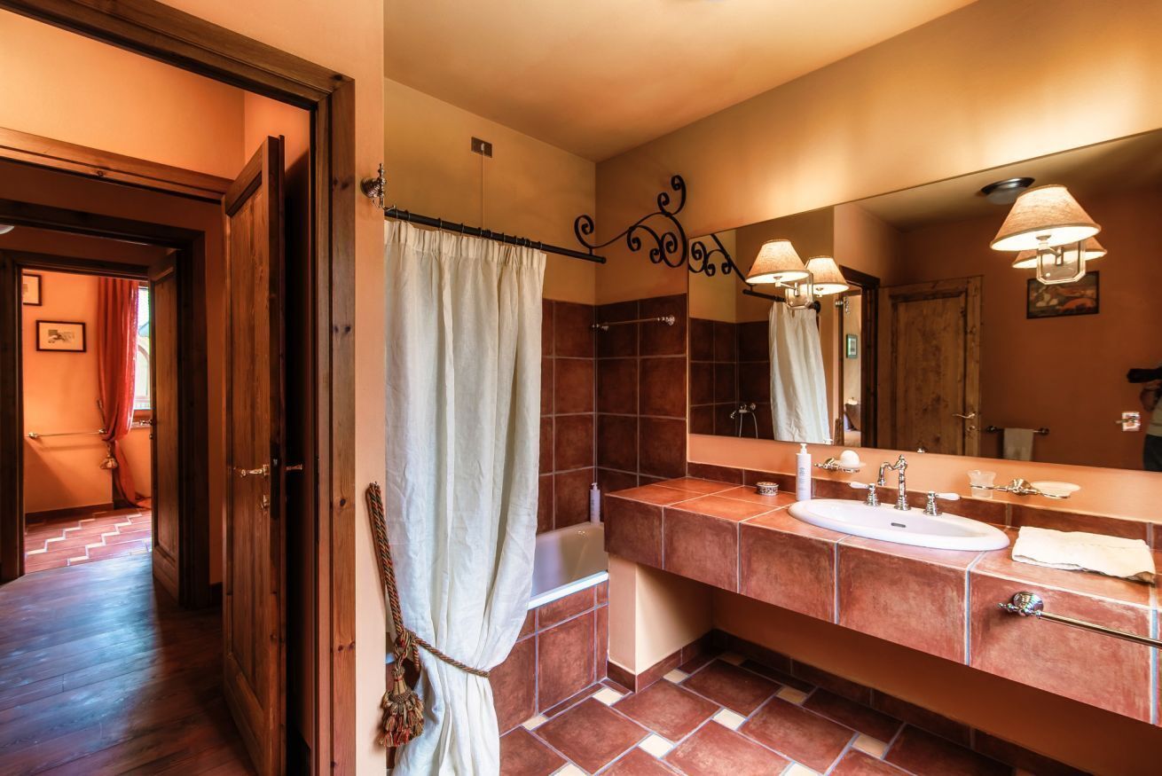A bathroom with a bathtub, two sinks, a large mirror, and a shower curtain.