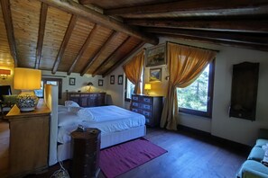 A bedroom with a wooden ceiling, a bed, a dresser, a nightstand, a lamp, and a window with curtains. - Villa Oasi - My Home in Como (Canzo)