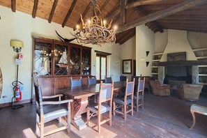 A dining area with a wooden table and chairs, a chandelier, and a fireplace. - Villa Oasi - My Home in Como (Canzo)