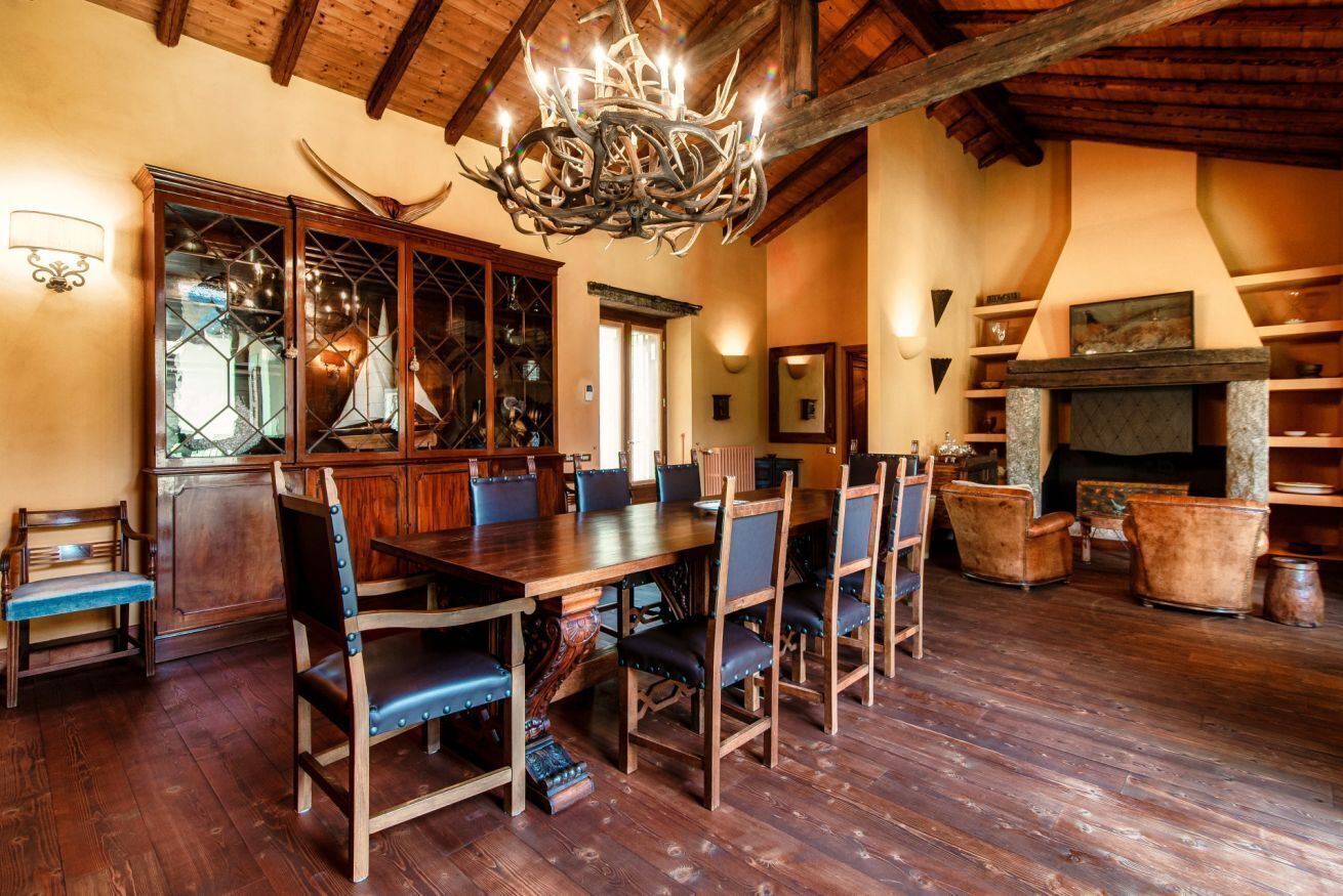 Zona pranzo con tavolo e sedie in legno, un lampadario e un camino.