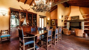 A dining area with a wooden table and chairs, a chandelier, and a fireplace. - Villa Oasi - My Home in Como (Canzo)