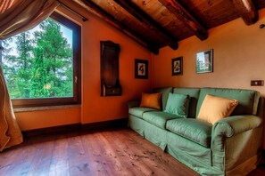 A room with a wooden ceiling, a green sofa, a window with curtains, and framed pictures on the wall. - Villa Oasi - My Home in Como (Canzo)