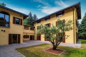 A two-story building with a courtyard, wooden shutters, and a tree. - Villa Oasi - My Home in Como (Canzo)