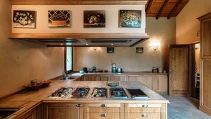 A kitchen with a large island, wooden cabinets, and a high ceiling with exposed beams. - Villa Oasi - My Home in Como (Canzo)