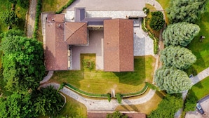 An aerial view of a building with a large, flat-roofed structure, surrounded by well-maintained lawns and trees. - Villa Oasi - My Home in Como (Canzo)