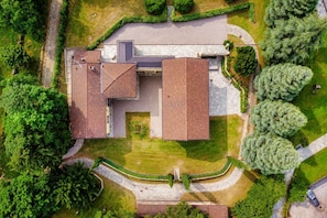 An aerial view of a building with a large, flat-roofed structure, surrounded by well-maintained lawns and trees. - Villa Oasi - My Home in Como (Canzo)