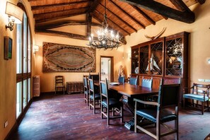 A dining area with a wooden table and chairs, a chandelier, and a large rug. - Villa Oasi - My Home in Como (Canzo)