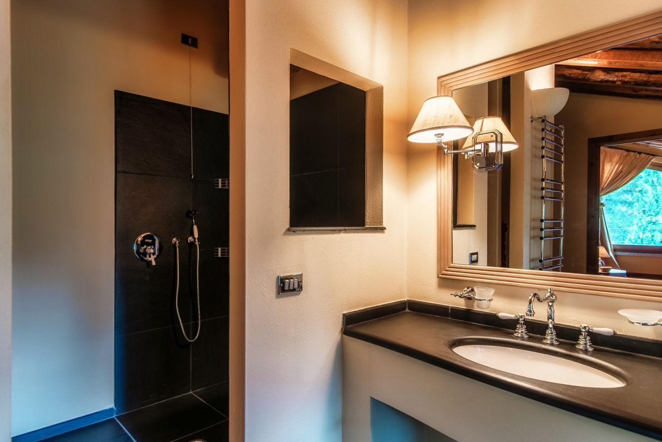 Un bagno con doccia scura, uno specchio grande e un lavabo doppio con mobile.