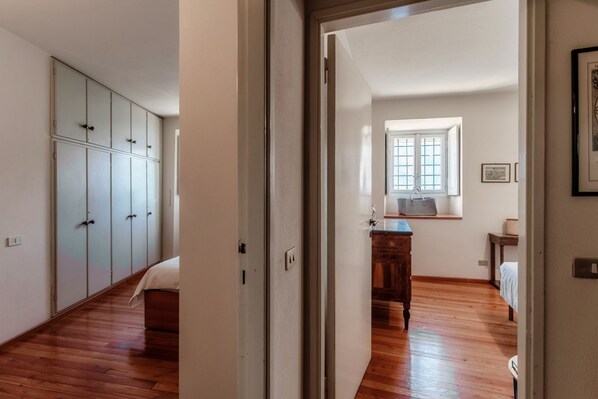 A room with a wooden floor, a bed, a wardrobe, and a window with a view.