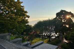 A garden with a stone staircase, a lawn, and a view of distant mountains.