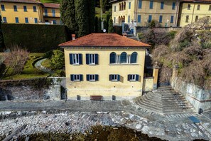 A building with a red-tiled roof, multiple windows, and a stone staircase leading to a higher level.
