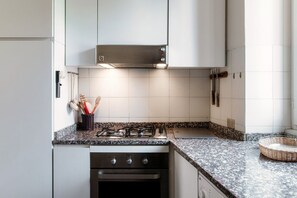 A kitchen with white cabinets, a gas stove, an oven, and a tiled backsplash.