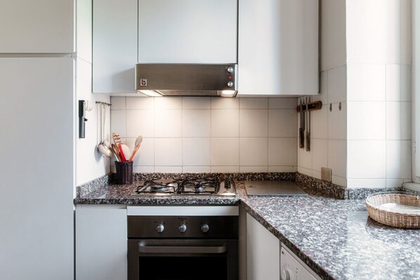 A kitchen with white cabinets, a gas stove, an oven, and a tiled backsplash.